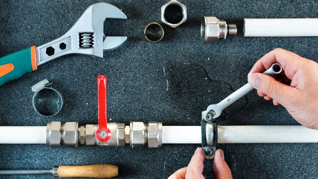 Plumber repairing a pipe valve with an adjustable wrench in DeBary