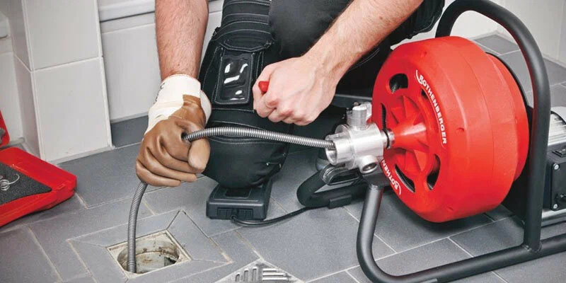 Plumber using a drain-cleaning machine in DeBary