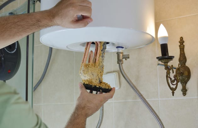 Technician removing mineral buildup from a water heater in DeBary