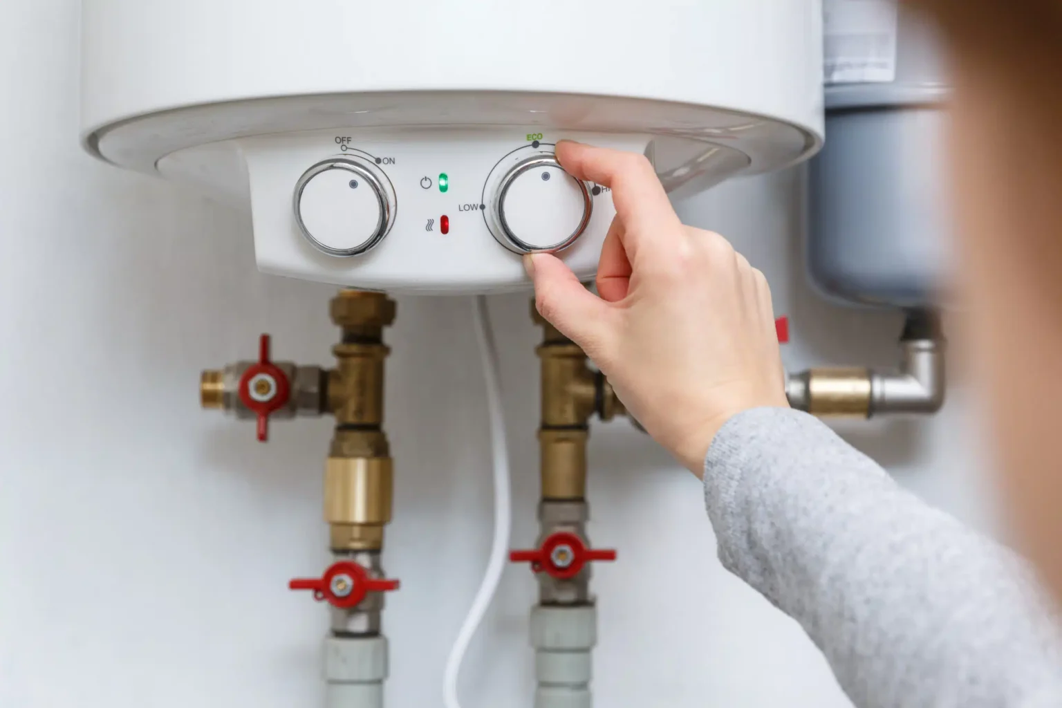 Homeowner adjusting the temperature controls on a water heater in DeBary